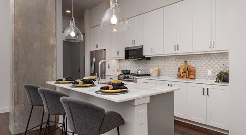 A kitchen with a table set for two with a white table cloth and two chairs.