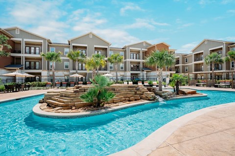 a swimming pool with palm trees in front of an apartment building