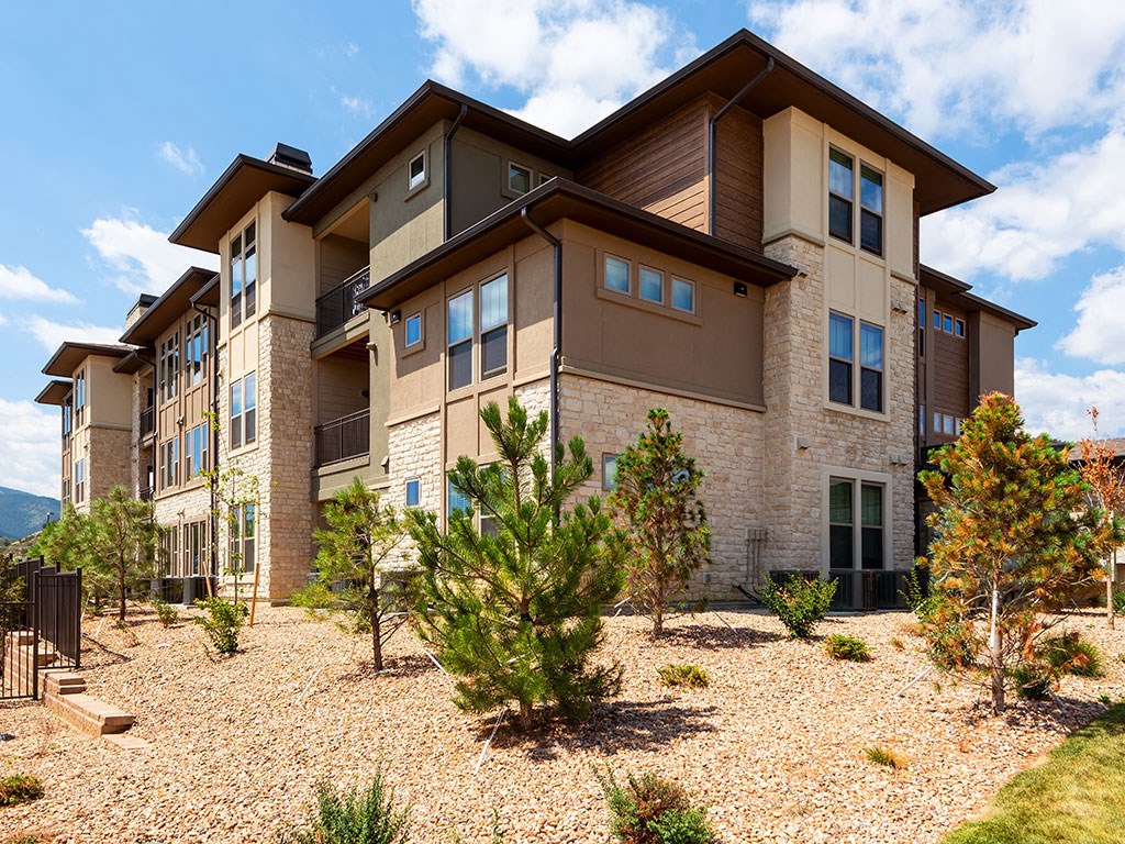 an apartment building with gravel and trees in front of it