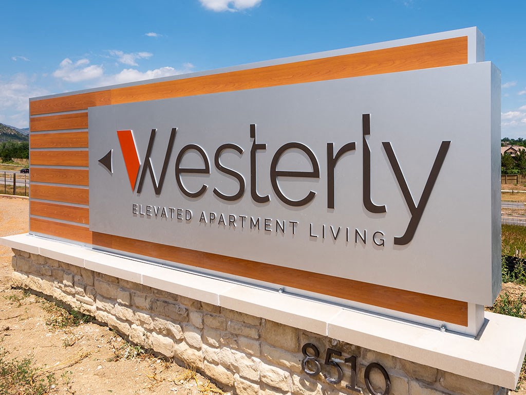 a sign for a westerniya retirement apartment living facility on a stone wall