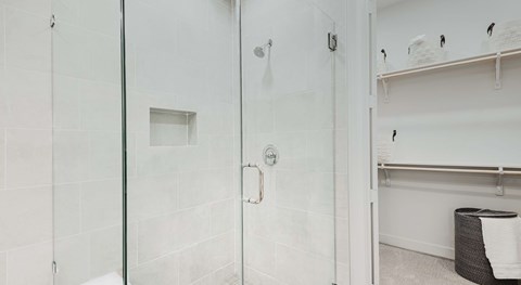 A white bathroom with a glass shower door and a towel rack.