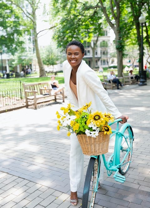 a woman riding a bike with a basket of flowers
