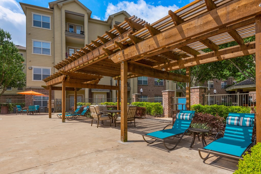 a patio with chairs and a wooden pergola