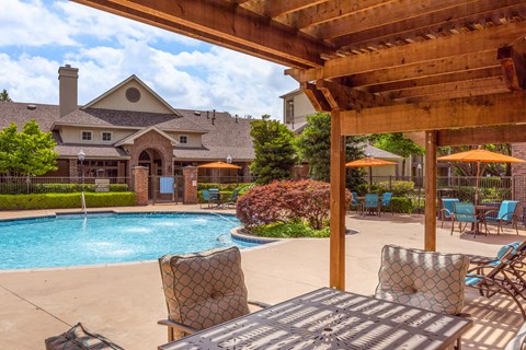 a swimming pool with patio furniture and a house in the background