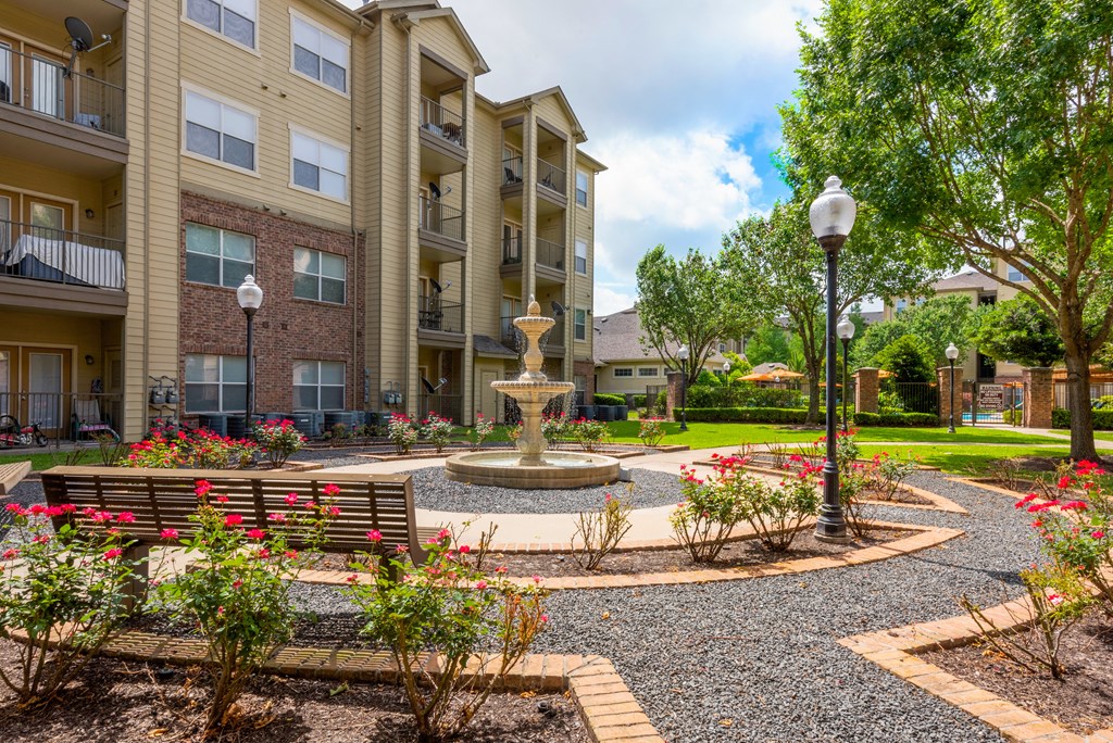 a courtyard with a fountain and benches in front of an apartment building