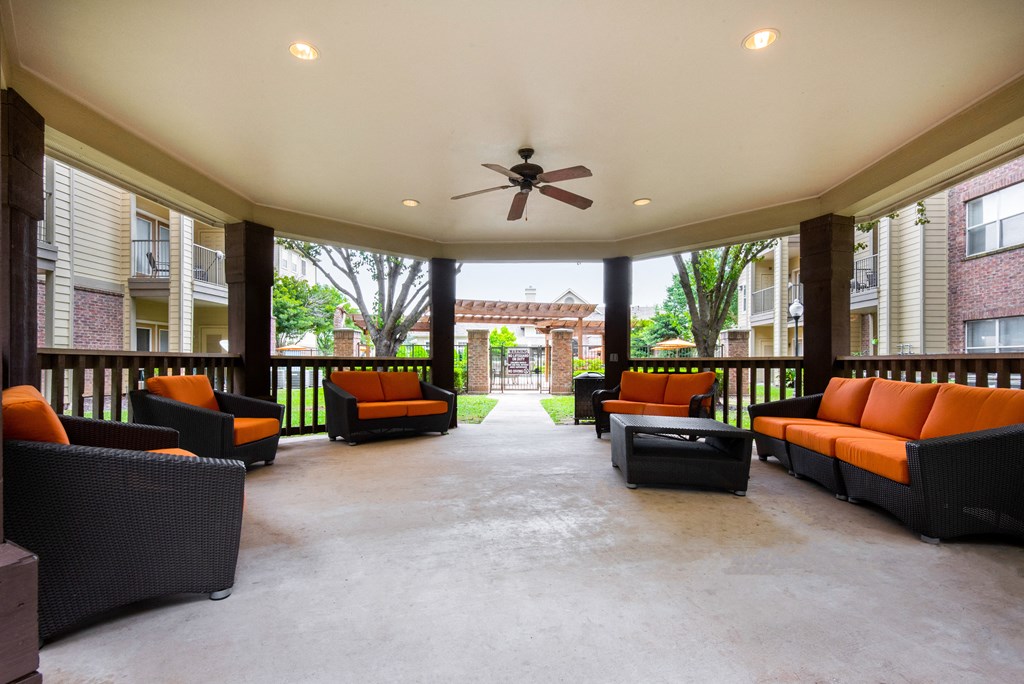 a covered patio with couches and a ceiling fan