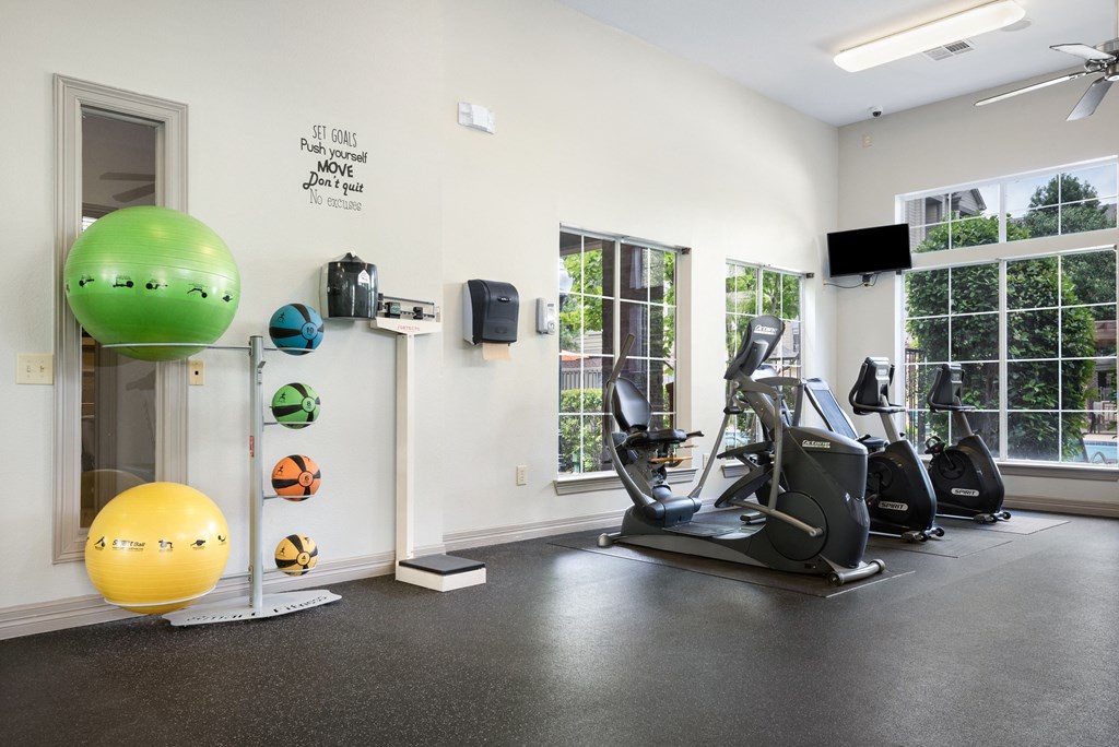 a gym with exercise equipment and a green ball on the floor