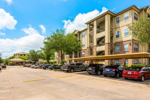 a parking lot with cars parked in front of an apartment building