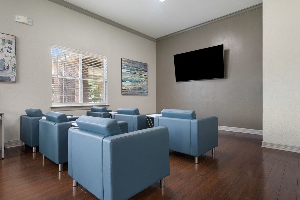 a waiting room with blue chairs and a tv on the wall