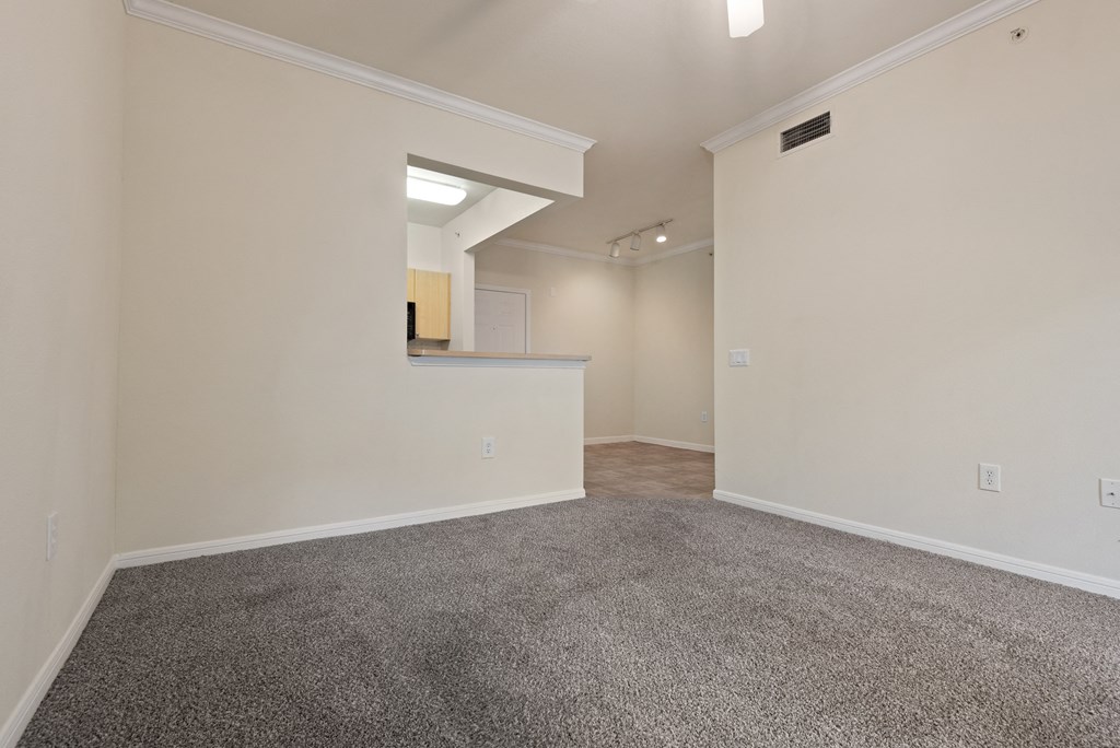 an empty living room with carpet and a kitchen