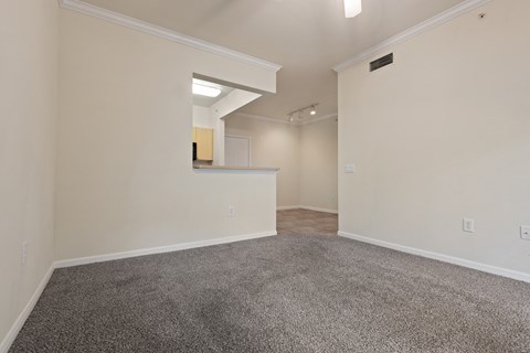 an empty living room with carpet and a kitchen