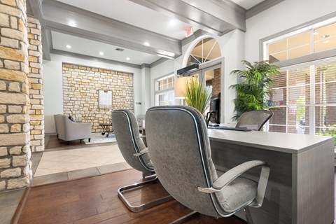 an office with a desk and chairs in front of a brick wall