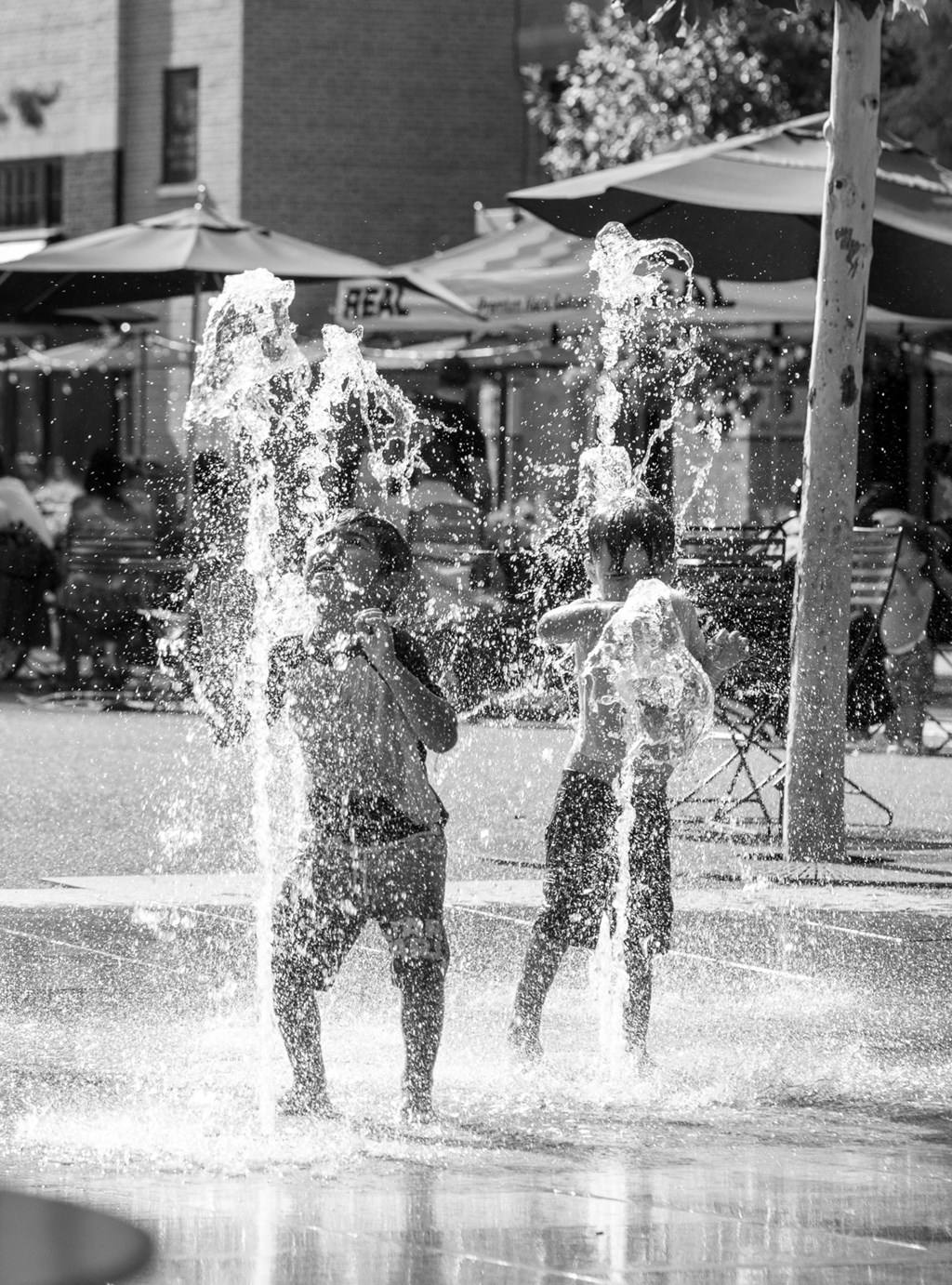 Two people playing in a water fountain.