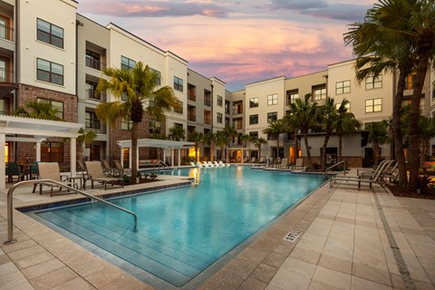 a swimming pool in front of an apartment building at sunset