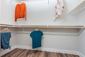 a walk in closet with clothes hanging on the wall