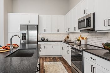 a kitchen with white cabinets and black countertops