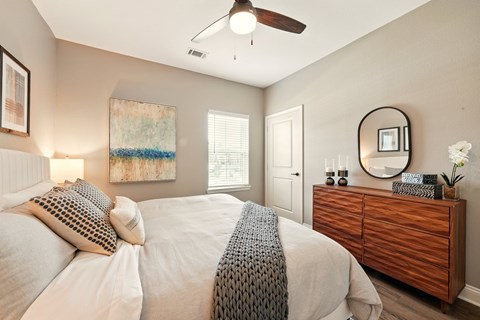 A bedroom with a bed, dresser, and a ceiling fan. at Beau Chene Lake Charles Apartments, Lake Charles, LA, 70605