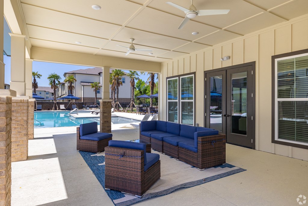 patio area of clubhouse with couches and a pool at Beau Chene Lake Charles Apartments in Lake Charles, LA 70605