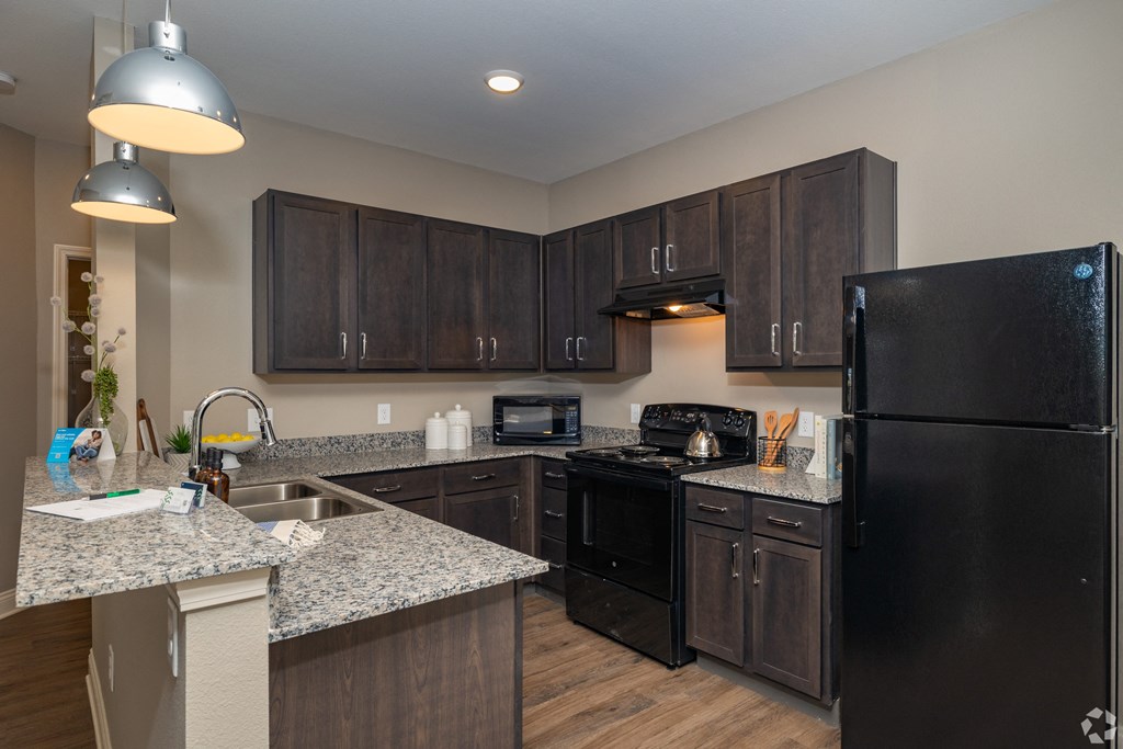 a kitchen with black appliances and granite counter tops at Beau Chene Lake Charles Apartments in Lake Charles, LA 70605