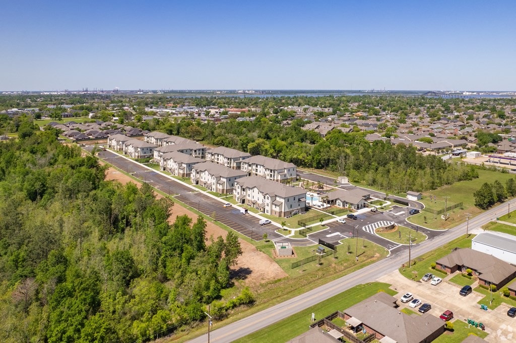 an aerial view of a parking lot with buildings and trees at Beau Chene Lake Charles Apartments in Lake Charles, LA 70605