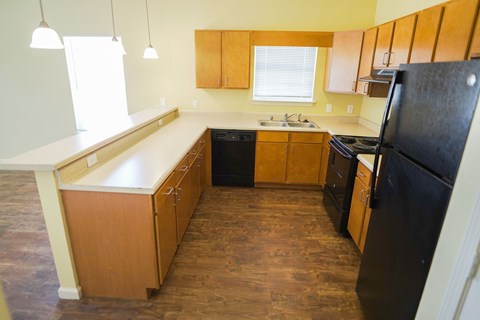 an empty kitchen with wooden cabinets and a black refrigerator
