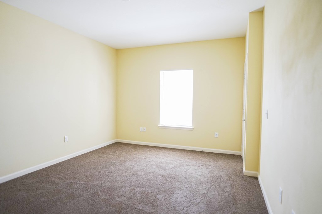 an empty room with a window and carpet
