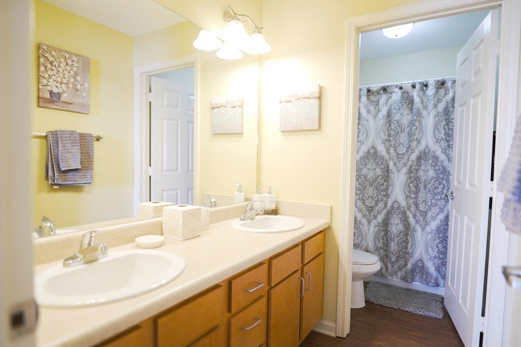 A bathroom with double white sinks and a mirror above it.
