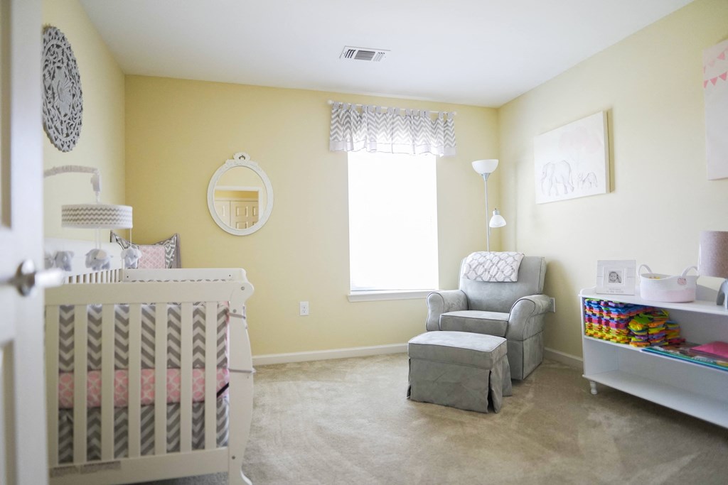 A baby nursery with a crib, chair, and changing table.