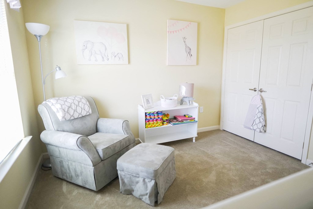 A room with a chair, ottoman, and a table with toys on it.