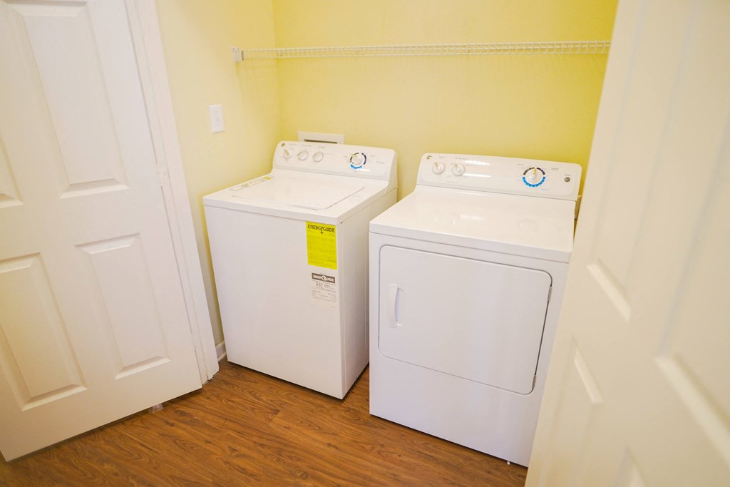 A white washing machines and dryerin a small laundry room.