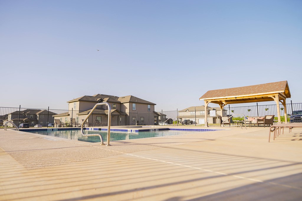 A swimming pool with a sunshade and a building in the background.