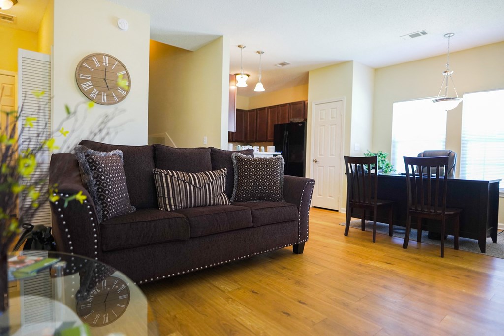 a living room and dining room with a couch and a clock