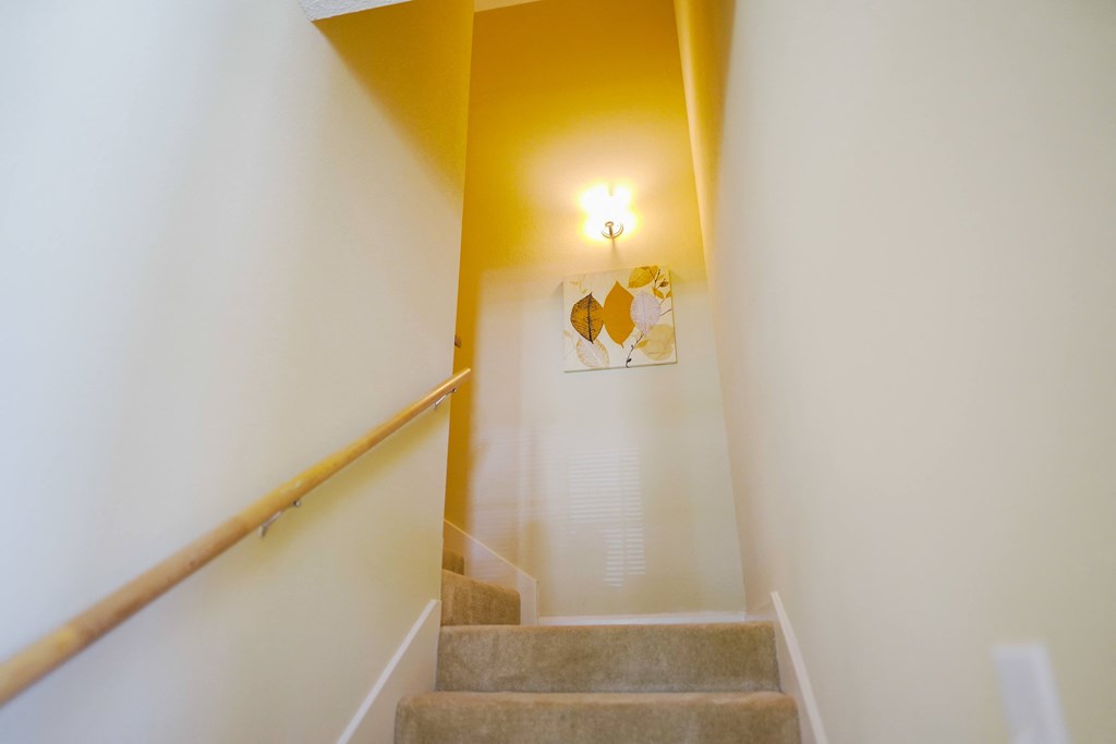 a view down the stairs of a hallway with a yellow ceiling and a yellow light