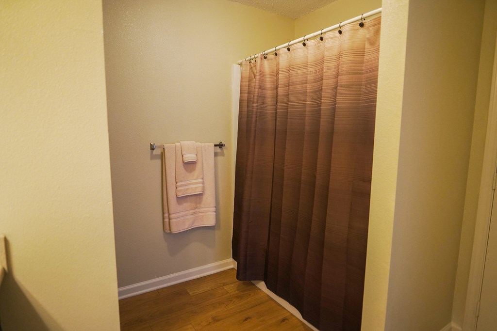 a small bathroom with a shower curtain and towels on a towel rack