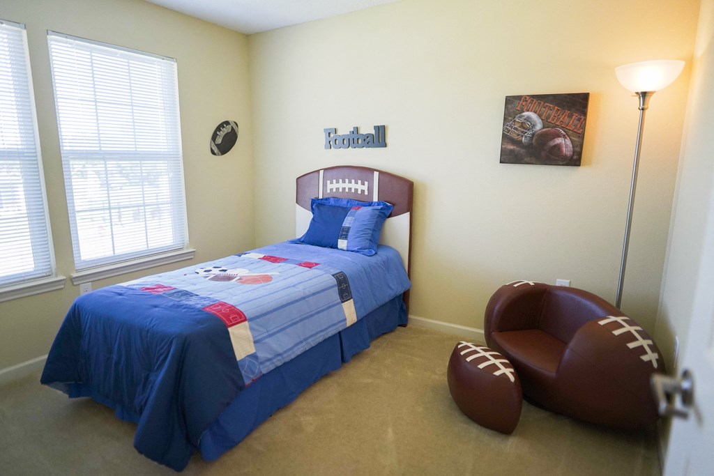 a bedroom with a bed and a football chair in it