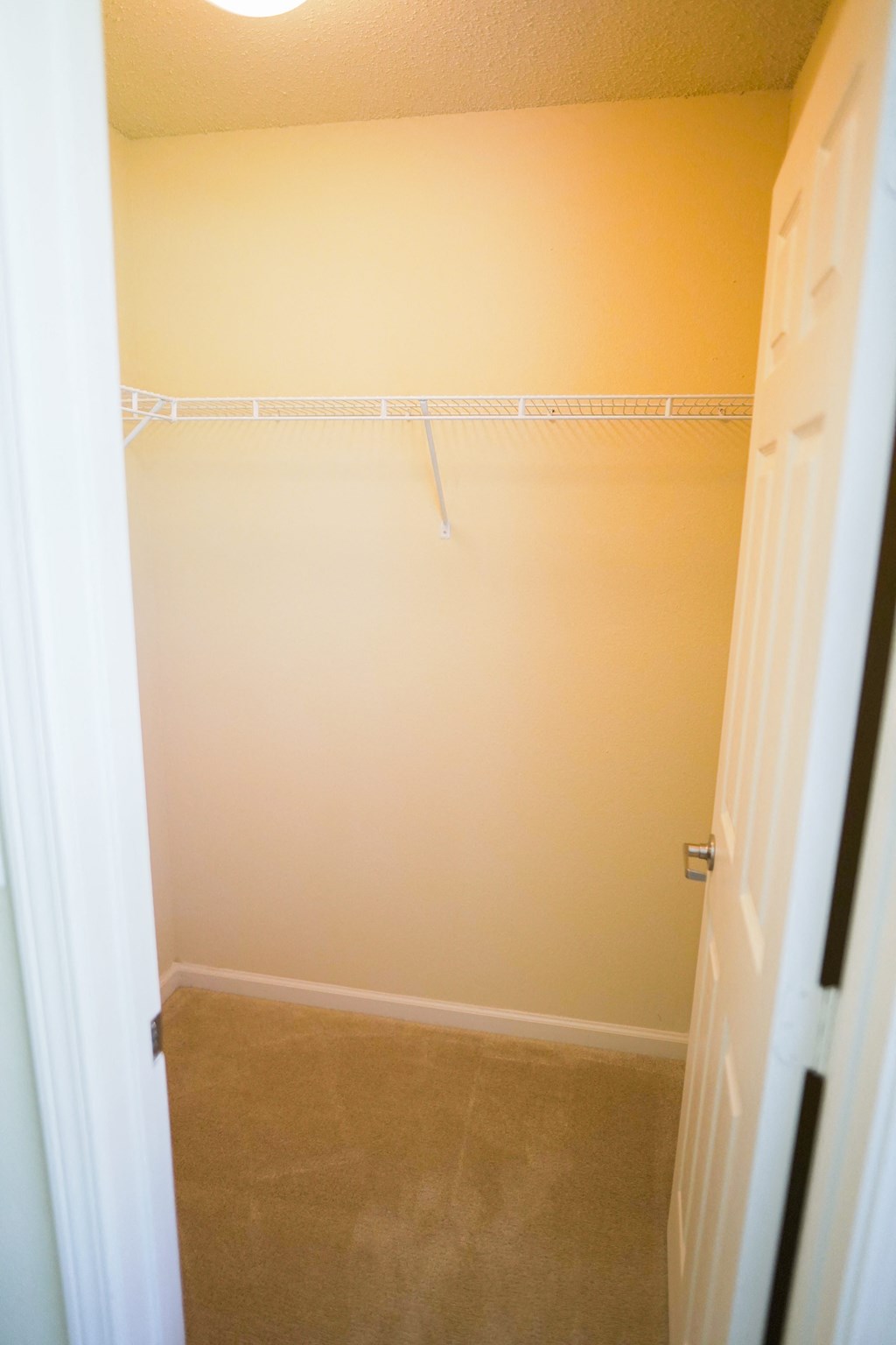a walk in closet with a white rack and a door