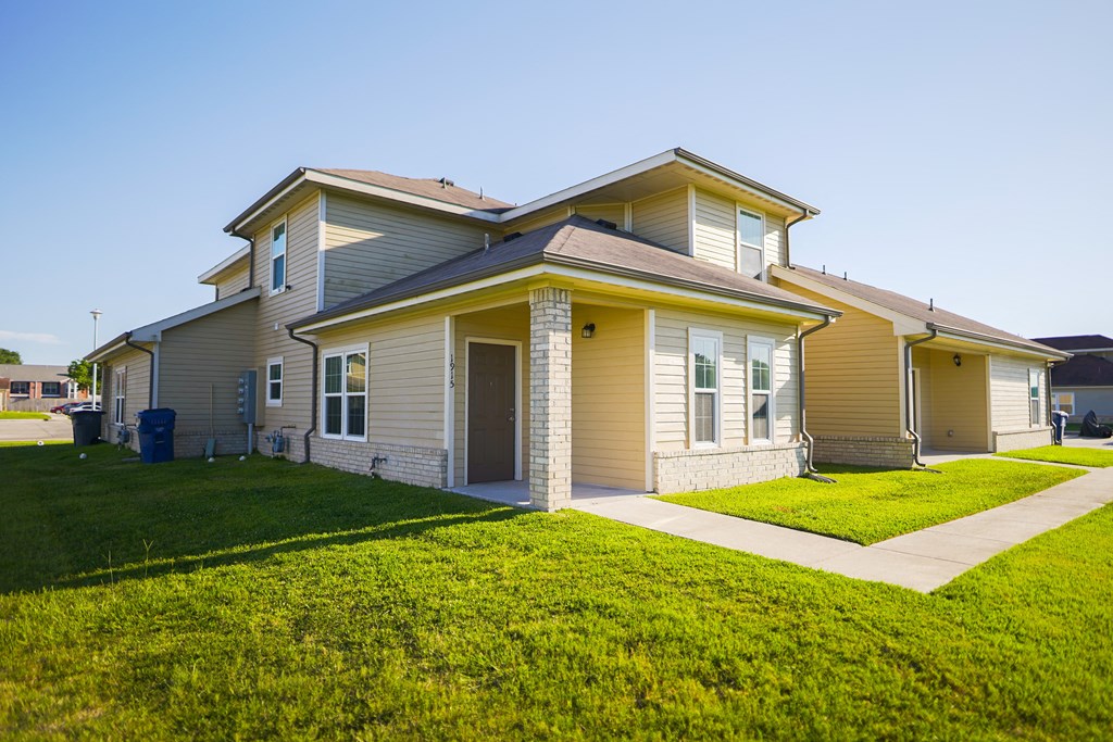 a house with a lawn and a sidewalk in front of it