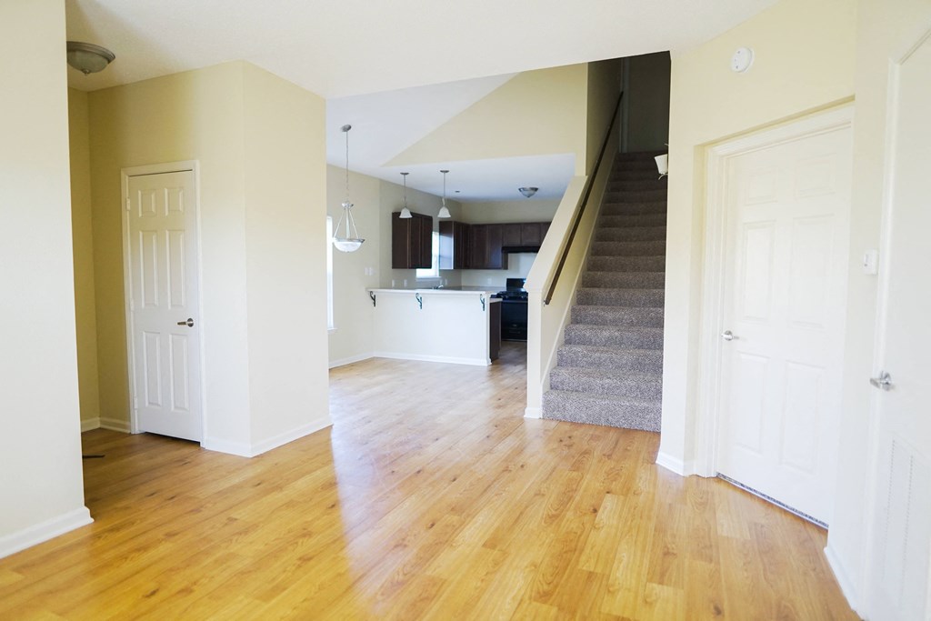 an empty living room with a hard wood floor and stairs