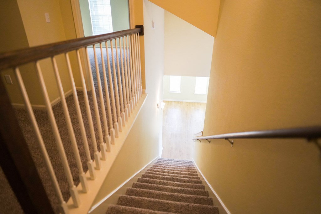 a view down the stairs of a hallway with carpeting and a carpeted staircase