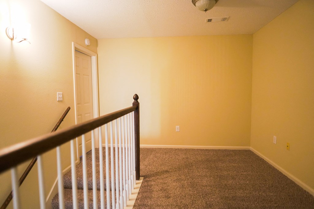 a room with a carpeted floor and a staircase    and a door