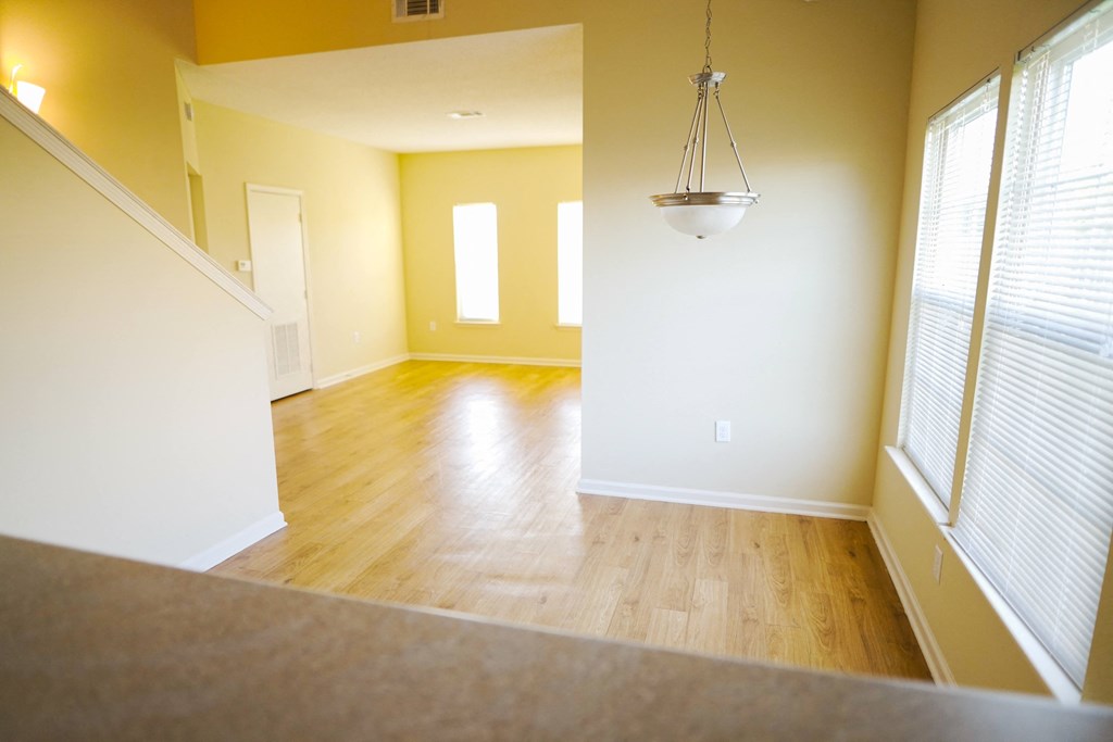 an empty living room with a hard wood floor and a chandelier