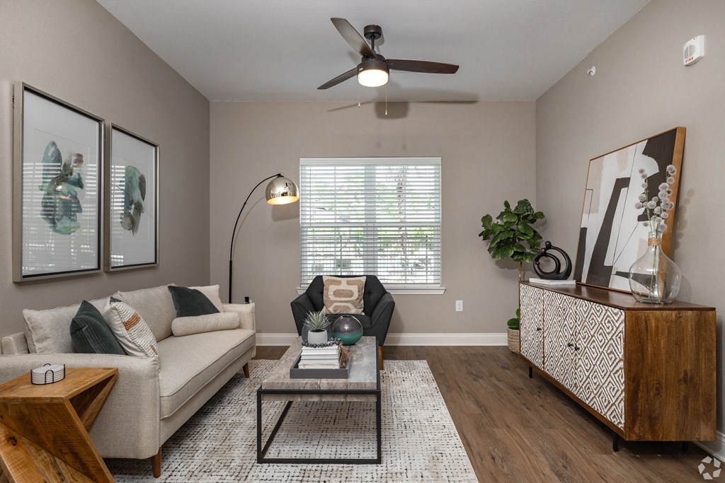 a living room with a couch and a ceiling fan at Beau Chene Lake Charles Apartments in Lake Charles, LA 70605