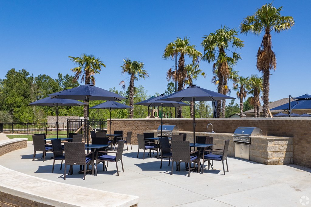 a patio area with tables and chairs and umbrellas at Beau Chene Lake Charles Apartments in Lake Charles, LA 70605