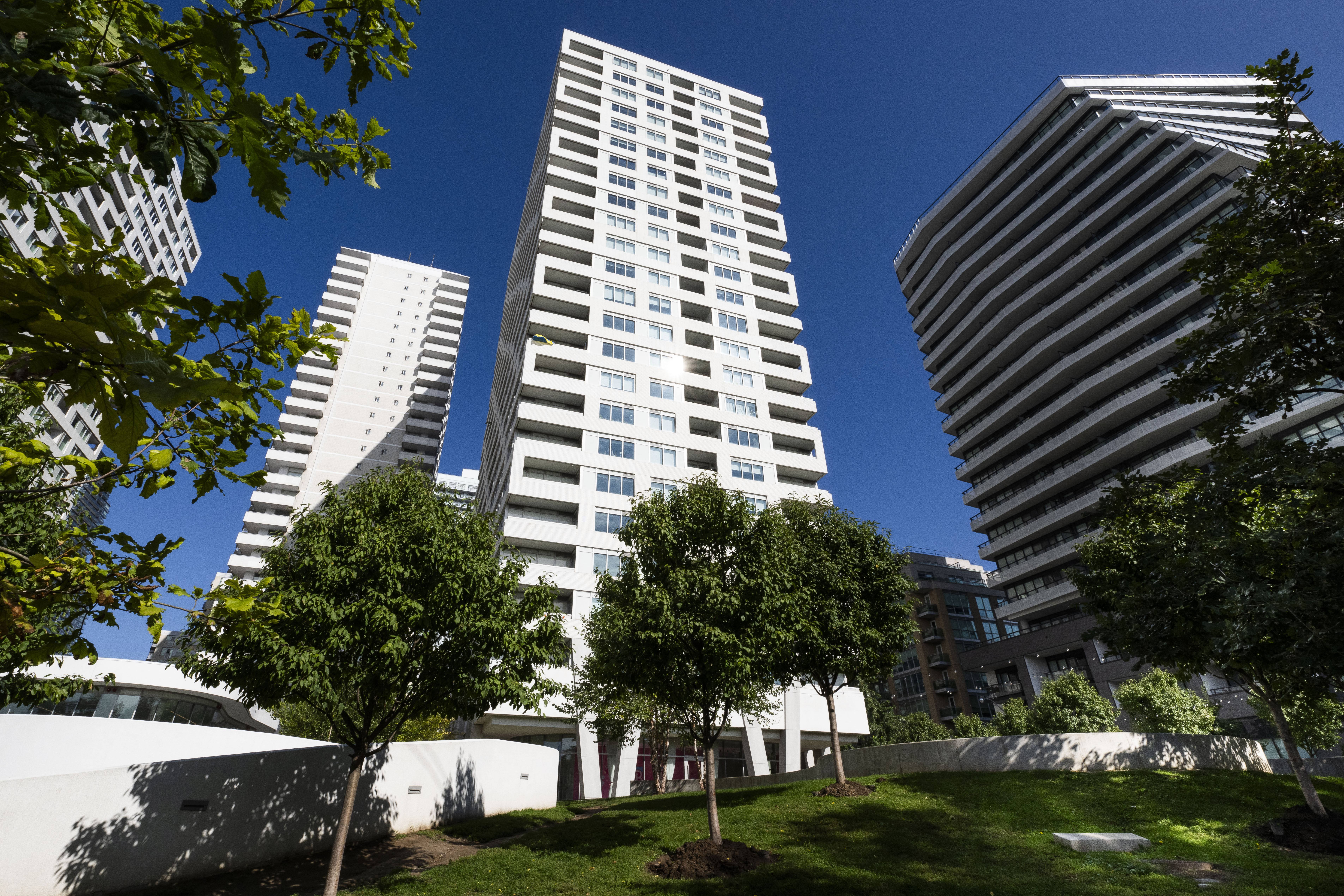 A tall white building stands in front of two other buildings.