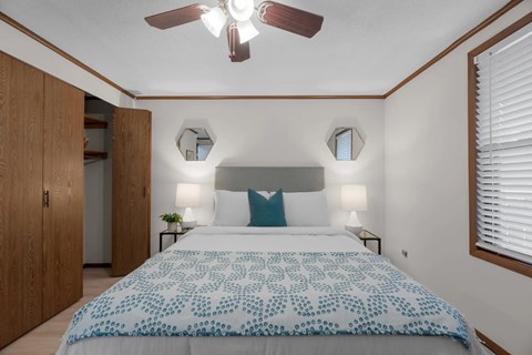 A bedroom with a bed, two lamps, and a ceiling fan.
