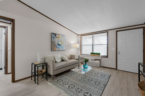 A living room with a couch, a table, and a painting on the wall.