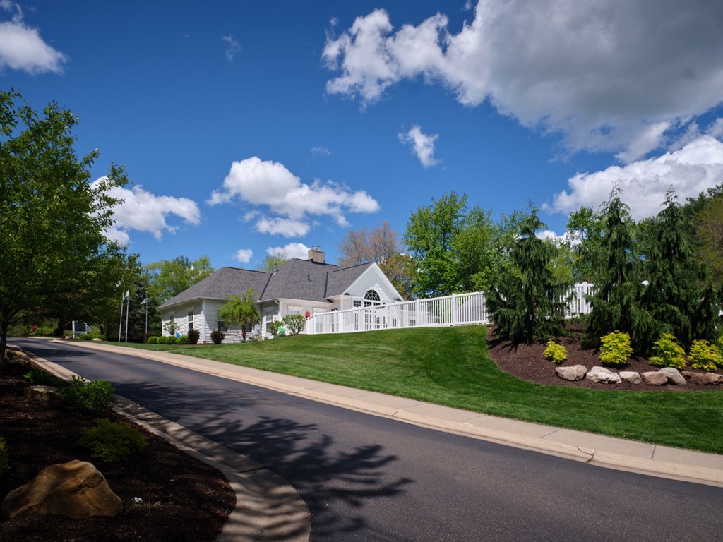 a white house on the side of a street with a road