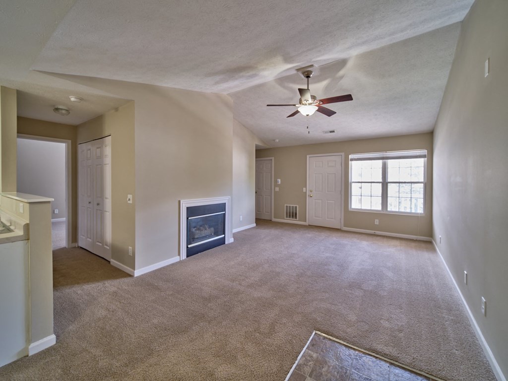 an empty living room with a ceiling fan and a fireplace