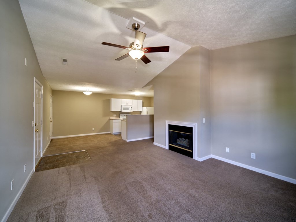 a empty living room with a fireplace and a ceiling fan