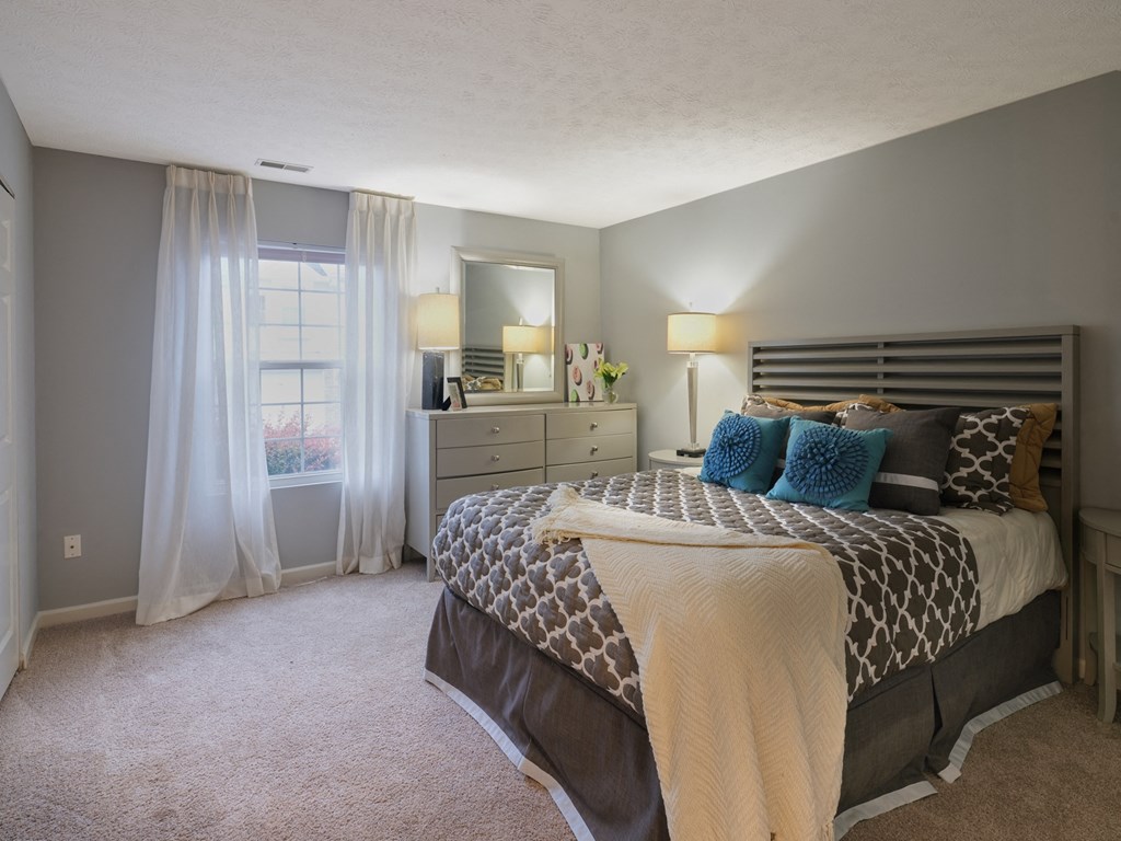 a bedroom with a bed and a dresser and a window